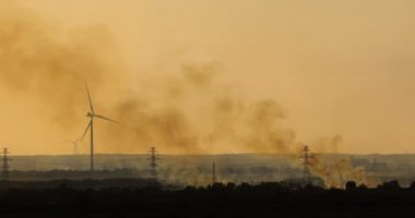 Rüzgâr jeneratörü ve alacakaranlıkta telefoto lensli ateşten çıkan duman.