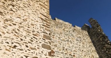 Bir ortaçağ taş kulesi, taştan bir duvar ve güneşli bir günde güneşli bir merdiven. Mavi gökyüzü. Düşük açı sağdan sola eğik.