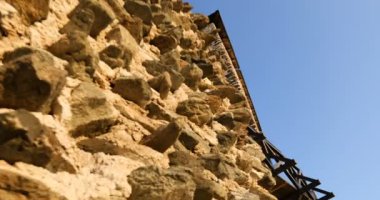 Kamera vinci, düzensiz şekilli taş duvar şeklindeki ortaçağ kalesinden. Kamera aşağıdan yukarıya hareket ediyor. Düşük açılı.