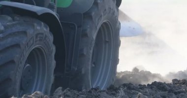 Traktör tekerleğinin ayrıntıları ve kuru tarlayı bir sürü tozla sürmek.