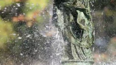 Su, metal heykellerin üzerine püskürtülmüş. Çeşmelerin bir kısmı yavaş çekimde bulanık arkaplanlı.