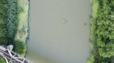 Eski bir demiryolu köprüsünün üzerinde karanlık bir nehirde kameralı bir drone ile hızlı uçuyor.