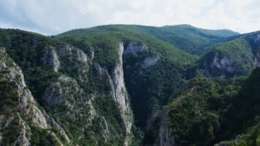 Dağların ortasındaki sık bir ormanla çevrili büyük bir kanyon üzerinde İHA ile uçmak