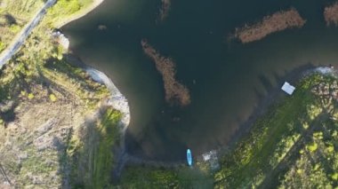 Büyük bir dağ gölü üzerinde insansız hava aracı ile uçmak arka planda bir baraj ile kalın bir orman ve kayalık bir sahil ile çevrili