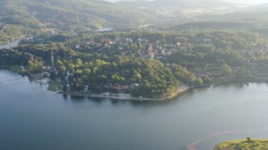 Güneşli bir günde, sık bir orman ve kayalık bir sahille çevrili güzel bir göl üzerinde uçmak.