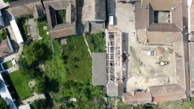 Güneşli bir yaz gününde, küçük bir köyde inşa edilmiş ve bitmemiş bir evin üzerinde dairesel hareketli bir insansız hava aracıyla uçmak.