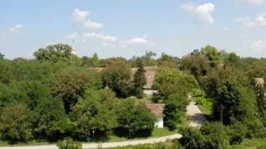 Güneşli bir günde, tarlaların ortasındaki küçük bir köyün üzerinden bir drone ile uçmak.