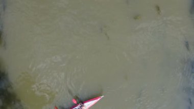 Bulutsuz güneşli bir günde birkaç kayıkla çamurlu bir nehrin üzerinden uçmak.