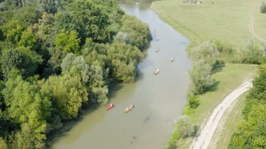 Güneşli ve bulutsuz bir günde birkaç kanoyla çamurlu bir nehrin üzerinde İHA ile uçmak
