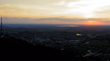 Küçük bir kasabanın üzerinde bulutlarla güzel bir gün batımı - İHA hareketli çekim