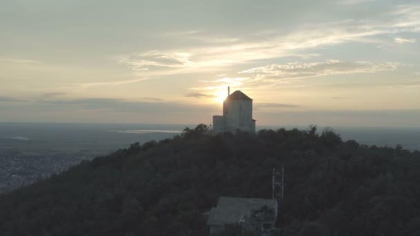 丘の上にある中世の石の塔の後ろに美しい夕日のドローンの移動ショット — ストック動画