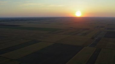 Güzel bir akşamın arka planında renkleri olan vahşi bir günbatımı manzaralı büyük bir arazide İHA ile uçmak