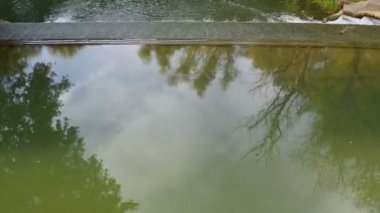 Bulutlu bir günde kırsal bir nehirde, küçük ama güzel bir şelalenin üzerinde bir dronla alçak uçuş.