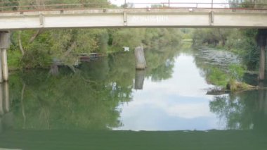 Bulutlu bir günde, küçük bir nehirde eski bir kırsal köprünün altında İHA ile uçmak
