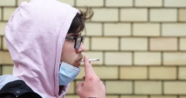 Skäggig Tonåring Som Röker Cigarett Med Skyddande Ansiktsmask Runt Hakan — Stockvideo