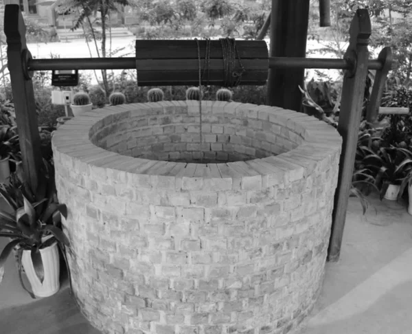 Dug water well is a structure created in the ground by digging to access groundwater in underground aquifers. The well water is drawn by hand winch using the buckets - black and white