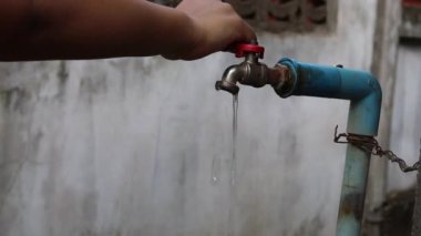 Genç el su tasarrufu için yavaş akan eski su musluğunu kapatıyor - su kavramını kurtarmak için.