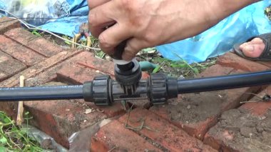 Çiftçi sebze bahçesi için su boruları kuruyor