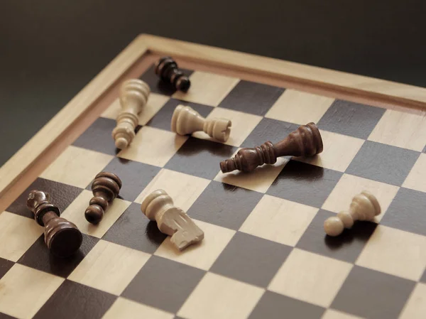 Настольная игра в шахматы. Деревянные шахматные фигуры лежат на шахматной доске. Понятие логика, стратегия, поражение — стоковое фото