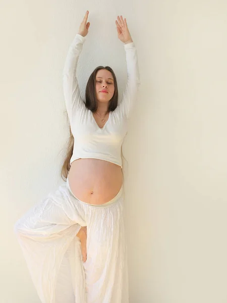 Jovem grávida se exercitando em casa, postura de ioga. O conceito de gravidez saudável, close-up no estômago . — Fotografia de Stock