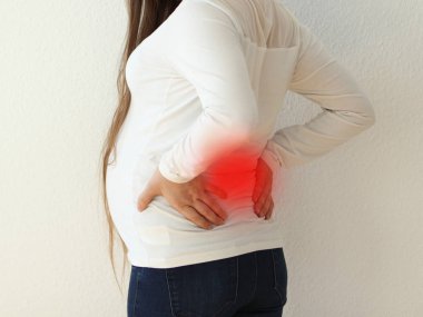 Sırt ağrısı genç bir hamile kadın. Beyaz bir arka plan üzerinde arkadan görünüm alınan. Hamile kadınlarda bel ağrısı