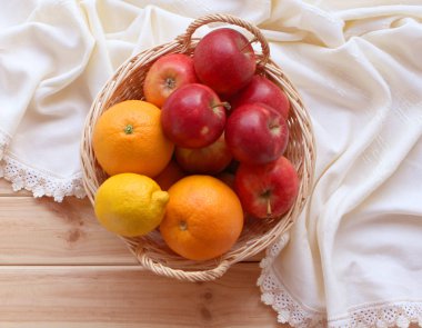 Bir hasır sepet taze kırmızı elma ile hangi yalan üzerinde hafif bir ahşap zemin üzerine beyaz peçete duruyor. En iyi görünüm, gıda ve sağlık kavramı