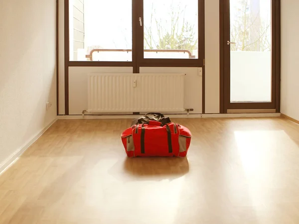 Una bolsa de deporte roja se encuentra en medio de una habitación vacía y luminosa . —  Fotos de Stock