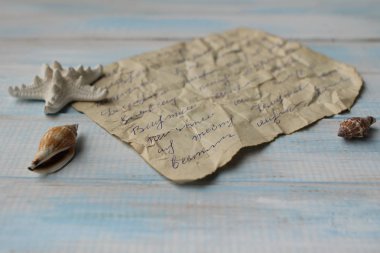 Yazıt ile eski kırışık kağıt, boş bir kavram olarak mavi ahşap arka planda yıldız balığı ve kopya alanı ile seyahat