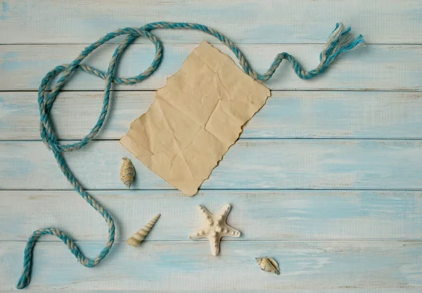 Muszle morskie, węzeł morski i gwiazda na niebieskim drewnianym tle i kartce papieru jako koncepcja wakacji z kopią przestrzeni — Zdjęcie stockowe