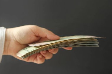 Erkek eller dolar kağıt tutun, karanlık bir arka planda yakın çekim