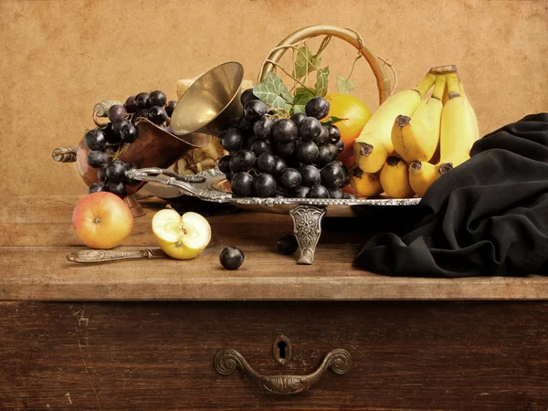 Виноград, бананы, яблоки и апельсины на красивом металлическом блюде с черной драпировкой ткани, рог изобилия — стоковое фото