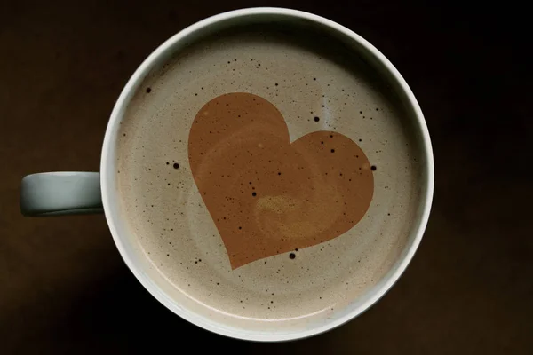 Bovenaanzicht van een kopje cappuccino koffie op de achtergrond, kunst op het hart. Liefde concept — Stockfoto