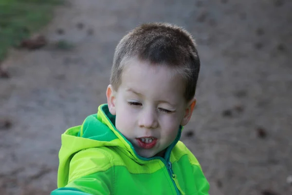 Menino pré-escolar em verde windbreaker é squinting, retrato emocional — Fotografia de Stock