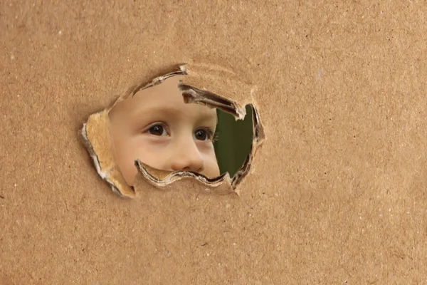 Espionagem do bebê, espreitando de um buraco em papelão, o conceito de sombreamento — Fotografia de Stock
