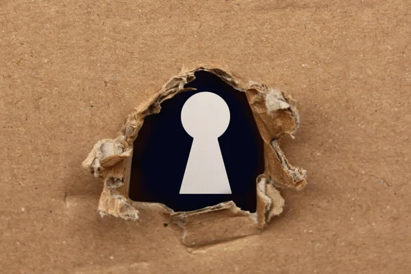 Το σύμβολο της κλειδαρότρυπας είναι ορατά πίσω από τις τρύπες σε το χαρτόνι, η έννοια της κατασκοπείας, peeping, μυστικά — Φωτογραφία Αρχείου