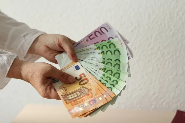 Kvinnliga händer håller euro sedlar, närbild på en ljus bakgrund — Stockfoto