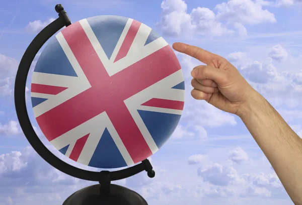 Degetul arătător al unei mâini de sex masculin indică un glob cu un steag național colorat Anglia — Fotografie, imagine de stoc