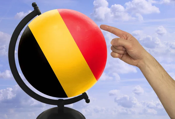 L'indice di una mano maschile indica un globo con una bandiera nazionale colorata belgium — Foto Stock