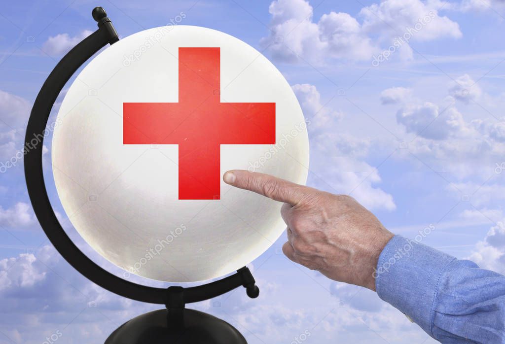 man's hand shows on a red cross - a symbol of mercy on a white globe