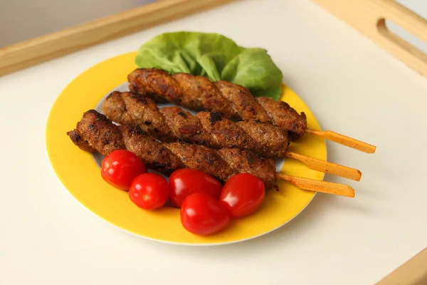 Gegrilltes Fleisch auf Spießen gebraten liegt auf einem gelben Teller mit frischem Gemüse, Tomaten, Salat, auf einem leichten Tablett — Stockfoto