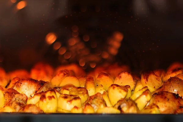 Gebackene Kartoffeln Nahaufnahme in roter Hintergrundbeleuchtung mit Bokeh auf dem Hintergrund des Ofenventilators — Stockfoto