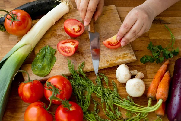 La mujer prepara la comida de hortalizas frescas: la zanahoria, la verdura, los tomates —  Fotos de Stock