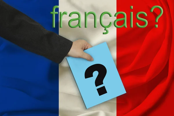 The teacher’s hand holds a question mark on the background of the inscription in French, \