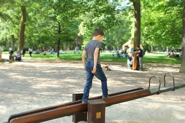 Menino andando em um balanço no parque, visão traseira, conceito de equilíbrio — Fotografia de Stock