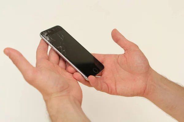 Teléfono móvil con un negro roto en pequeñas piezas de visualización en manos masculinas — Foto de Stock