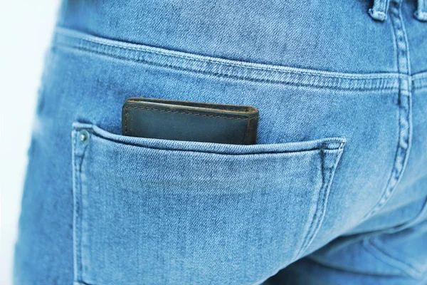 Bruine mannen portemonnee van kwaliteit echt leder ligt in de achterste zak van de blauwe jeans van mannen — Stockfoto
