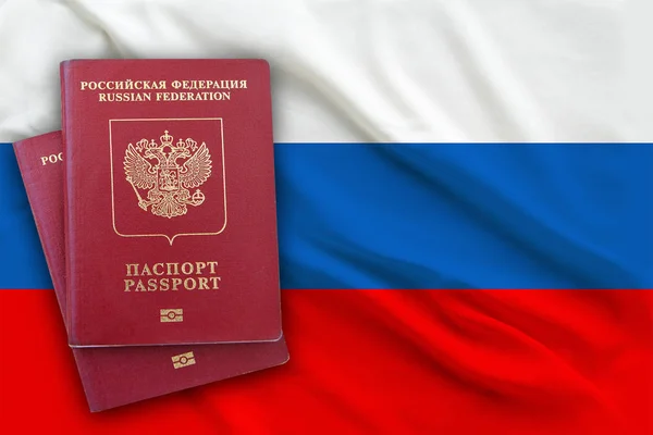 Dwa paszporty obywatela Federacji Rosyjskiej leżącego na szczycie siebie na tle rosyjskiej flagi, skopiuj przestrzeń w centrum — Zdjęcie stockowe