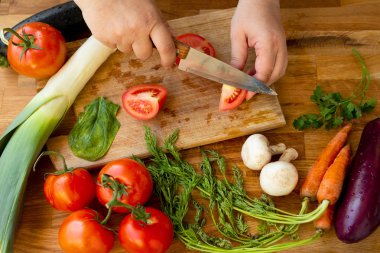 Kadın domatesleri bıçakla kesiyor.