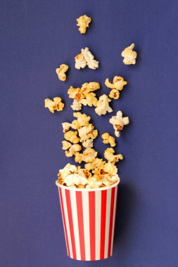 aromalı gevrek patlamış mısır bir leylak arka plan üzerinde çizgili beyaz-kırmızı kağıt fincan içine yukarıdan damlayan, kopya alanı