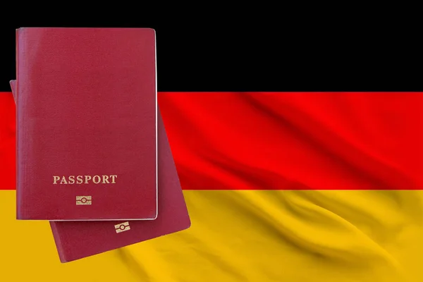 Two passports lying on each other against the background of the flag of Germany, copy space, naturalization and immigration concept — Stock Photo, Image